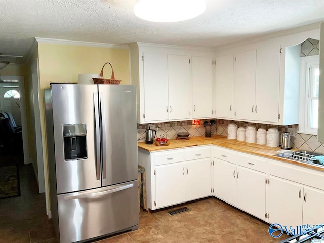 kitchen with white cabinets, decorative backsplash, stainless steel fridge with ice dispenser, a textured ceiling, and light tile patterned floors