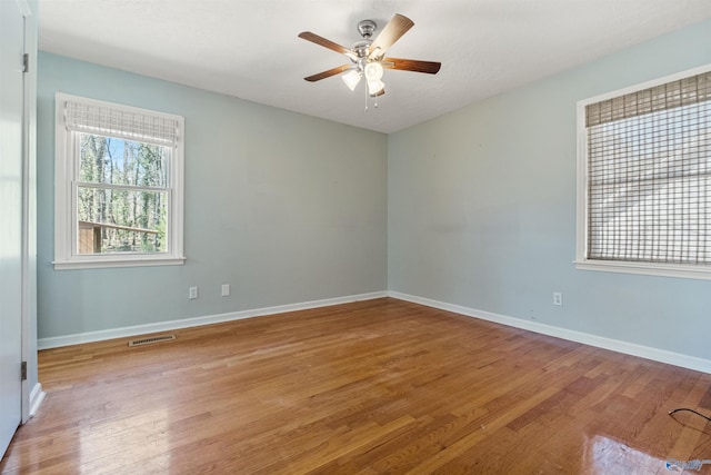 unfurnished room with a ceiling fan, visible vents, light wood finished floors, and baseboards