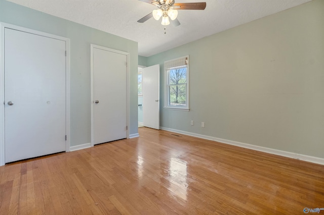 unfurnished bedroom featuring a textured ceiling, a ceiling fan, baseboards, and wood finished floors