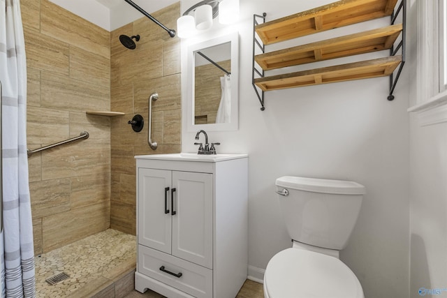 bathroom with vanity, toilet, and tiled shower