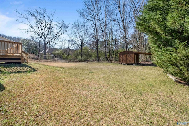 view of yard with an outbuilding, a storage unit, a deck, and fence