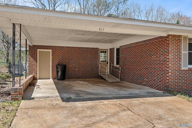 doorway to property with brick siding and an attached carport