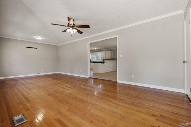 empty room featuring visible vents, ceiling fan, ornamental molding, and hardwood / wood-style flooring