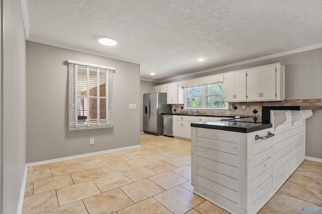 kitchen with stainless steel appliances, dark countertops, white cabinets, and ornamental molding