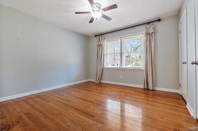 spare room featuring baseboards, a textured ceiling, ceiling fan, and light wood finished floors