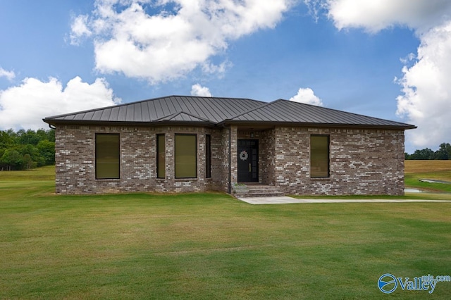 view of front facade with a front yard, a standing seam roof, brick siding, and metal roof