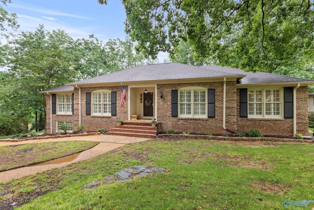 ranch-style home featuring a front yard, a shingled roof, and brick siding