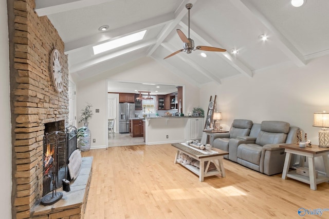 living room with recessed lighting, vaulted ceiling with skylight, light wood-style flooring, ceiling fan, and a fireplace