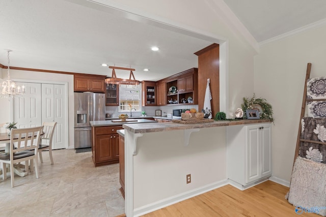 kitchen with crown molding, an inviting chandelier, a kitchen bar, stainless steel refrigerator with ice dispenser, and a peninsula
