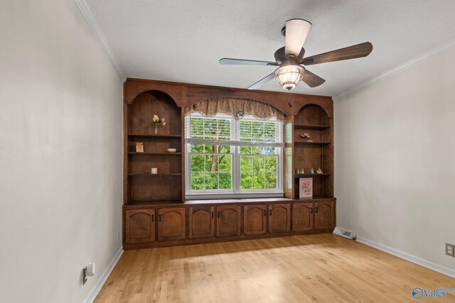 unfurnished dining area featuring light wood-style floors, ceiling fan, baseboards, visible vents, and crown molding