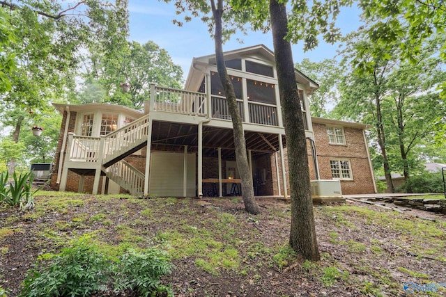 back of property featuring stairway, a deck, and a sunroom