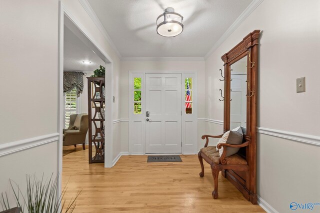 foyer entrance featuring a wealth of natural light, ornamental molding, light wood-style flooring, and baseboards