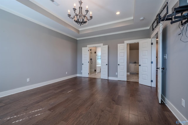 unfurnished bedroom with a notable chandelier, ensuite bathroom, dark wood-type flooring, and a raised ceiling