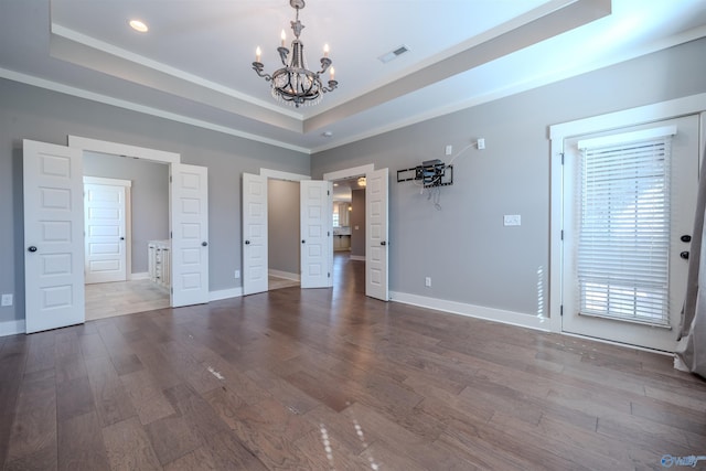 unfurnished bedroom featuring hardwood / wood-style flooring, an inviting chandelier, and a raised ceiling