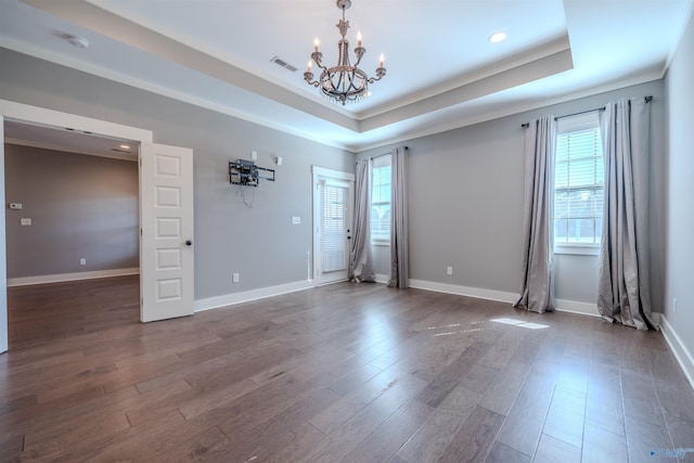 unfurnished room featuring a notable chandelier, a tray ceiling, and dark hardwood / wood-style flooring