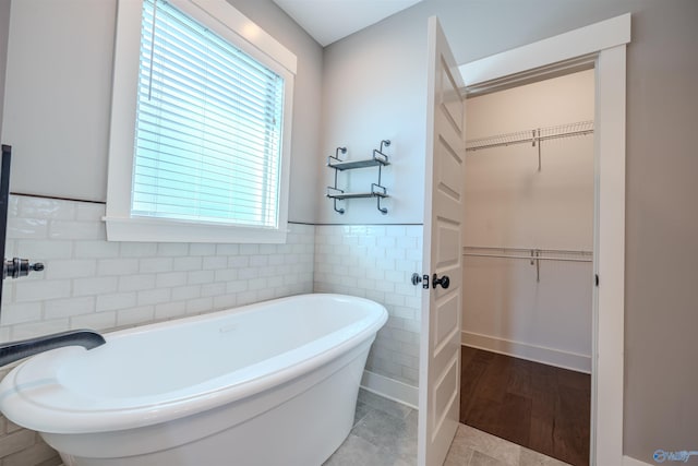 bathroom with tile patterned floors, tile walls, and a bathing tub