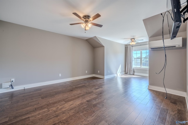 additional living space with a wall unit AC, dark wood-type flooring, and ceiling fan