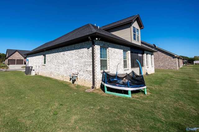 view of home's exterior featuring a garage, a trampoline, and a lawn