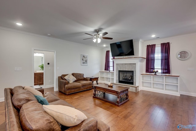 living room featuring crown molding, a fireplace, ceiling fan, and hardwood / wood-style flooring