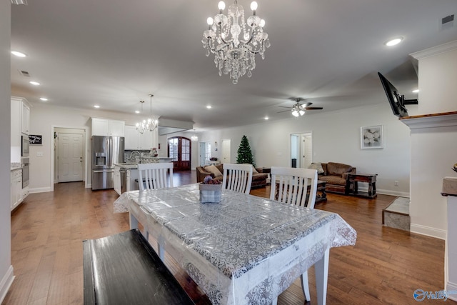 dining area featuring dark hardwood / wood-style flooring, ceiling fan with notable chandelier, and crown molding