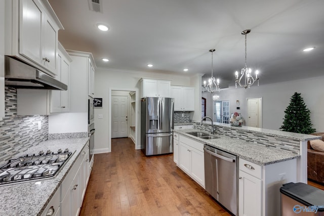 kitchen with sink, white cabinetry, backsplash, stainless steel appliances, and decorative light fixtures