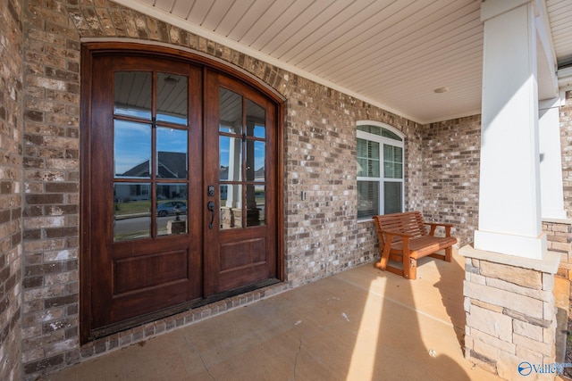 view of exterior entry featuring french doors and a porch