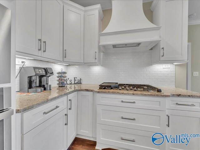 414 Wood Sage Ln, Huntsville, AL 35824 - kitchen with premium range hood, white cabinets, light stone countertops, decorative backsplash, and stainless steel appliances