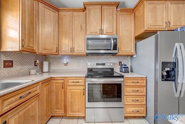 kitchen featuring light tile patterned floors, tasteful backsplash, a sink, stainless steel appliances, and light countertops