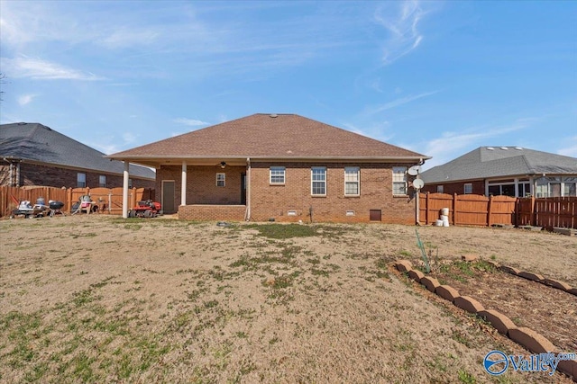 rear view of house with ceiling fan, a fenced backyard, and brick siding