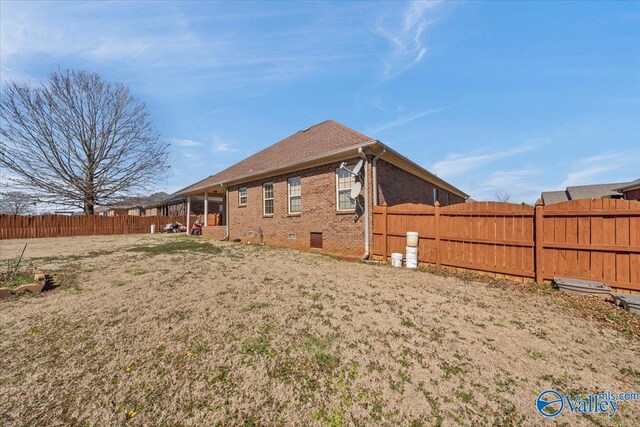 exterior space with brick siding, a fenced backyard, and a lawn