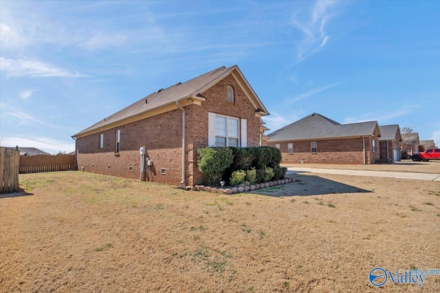 view of home's exterior featuring fence, a lawn, and brick siding
