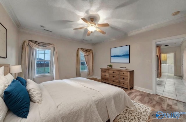 bedroom featuring washer and dryer, light wood-type flooring, crown molding, and visible vents