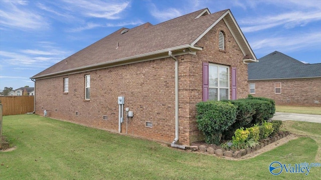 view of side of property featuring crawl space, a shingled roof, a yard, brick siding, and fence