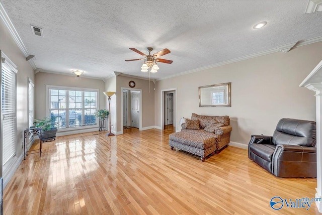 living room with a textured ceiling, visible vents, ceiling fan, baseboards, and light wood finished floors