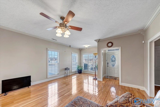 living room with a textured ceiling, wood finished floors, a ceiling fan, and baseboards