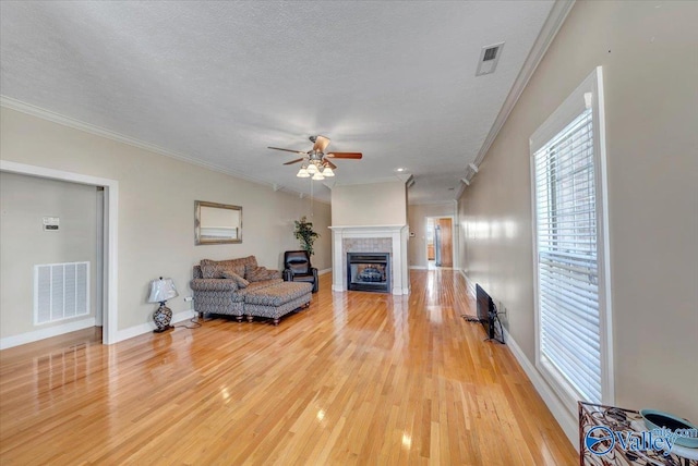 living area featuring a tile fireplace, visible vents, and ornamental molding