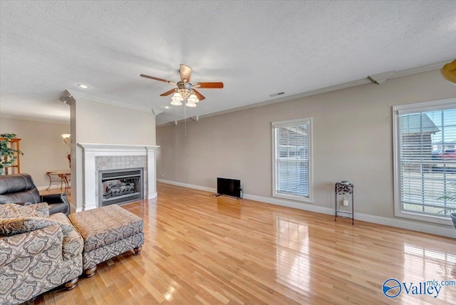 living room featuring wood finished floors, a ceiling fan, a textured ceiling, and ornamental molding