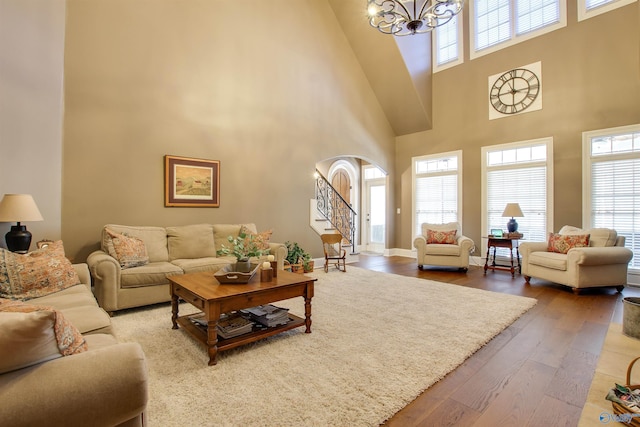 living room with a high ceiling, wood-type flooring, and a notable chandelier