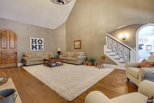 living room with high vaulted ceiling, wood-type flooring, and a notable chandelier