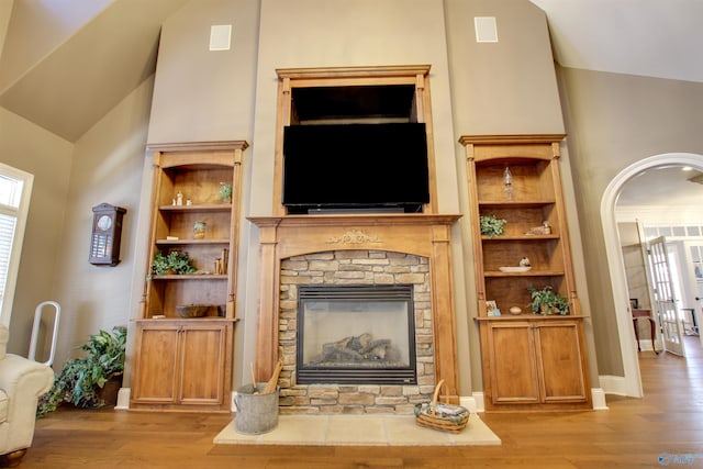 living room featuring vaulted ceiling, light hardwood / wood-style flooring, french doors, and a fireplace