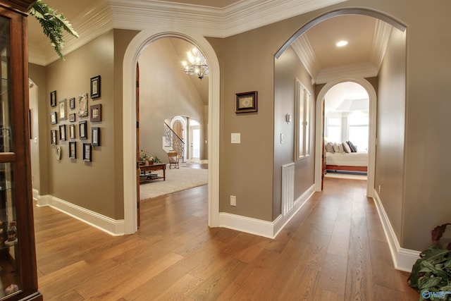 hall featuring light hardwood / wood-style flooring, ornamental molding, and a notable chandelier