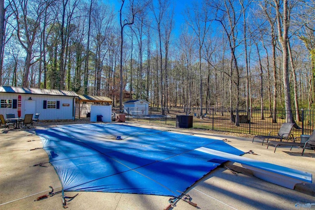 view of pool featuring an outdoor structure, a diving board, and a patio