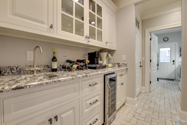 bar featuring light stone countertops, beverage cooler, white cabinetry, sink, and ornamental molding