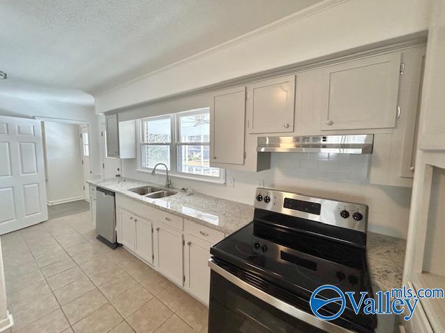 kitchen featuring sink, light tile patterned floors, tasteful backsplash, white cabinets, and appliances with stainless steel finishes