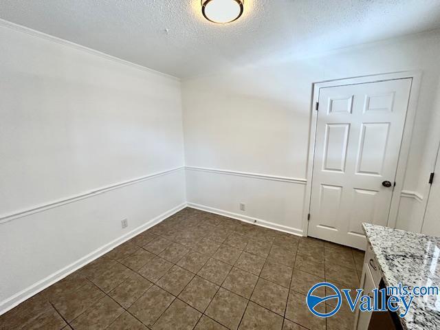 tiled spare room featuring a textured ceiling