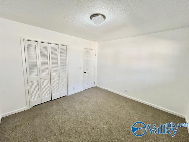 unfurnished bedroom featuring dark colored carpet, a textured ceiling, and a closet