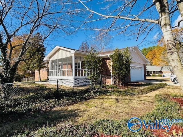 view of front of house featuring a garage, a front lawn, and a sunroom