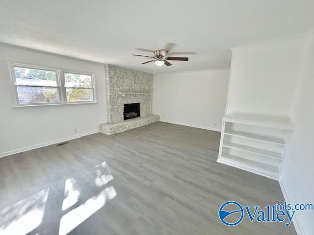 unfurnished living room featuring dark hardwood / wood-style flooring, ceiling fan, and a fireplace