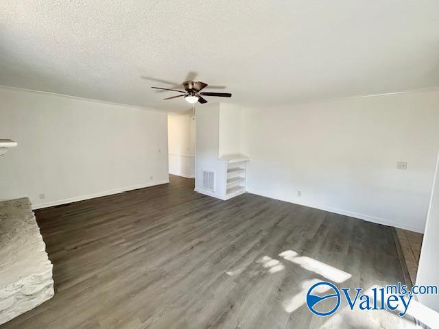 unfurnished living room with ceiling fan, dark wood-type flooring, and a textured ceiling