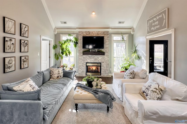 living room with lofted ceiling, ornamental molding, and a stone fireplace